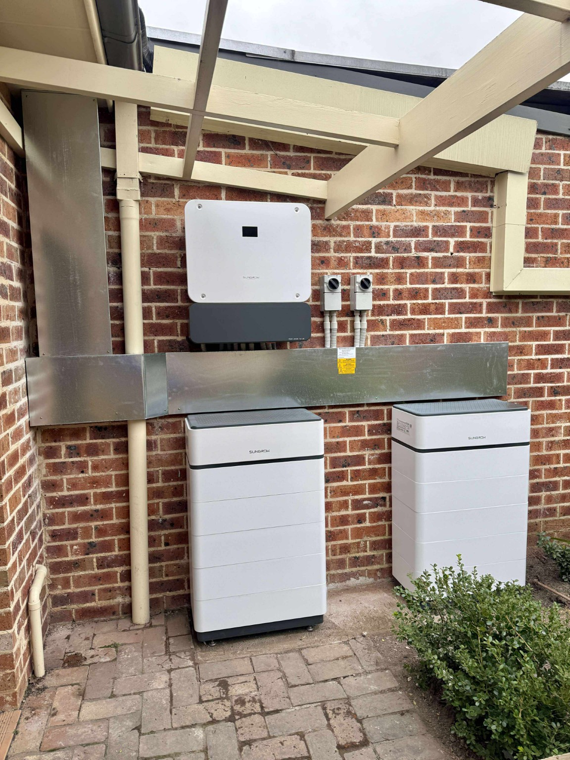 Two Sungrow battery units and inverter installed at a brick home
